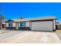 The home's exterior is designed with desert landscaping, a two-car garage, and an inviting yellow front door at 3437 E Acoma Dr, Phoenix, AZ 85032