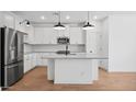 Modern kitchen features white cabinets, stainless steel appliances, and a center island with a sink at 42405 W Krista Dr, Maricopa, AZ 85138