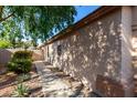 Side view of the home, showcasing landscaping, a neutral exterior, and a pathway at 42568 W Bunker Dr, Maricopa, AZ 85138