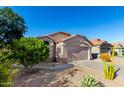 Single-story home showcasing desert landscaping, blue sky, and a well-maintained front yard at 42568 W Bunker Dr, Maricopa, AZ 85138