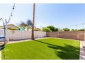 Spacious backyard features lush artificial turf, a white privacy fence, and a mature palm tree, perfect for outdoor activities at 4779 W Tulsa St, Chandler, AZ 85226