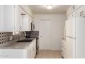 Functional kitchen with white cabinets, tiled backsplash, and essential appliances at 5323 E Dodge St, Mesa, AZ 85205