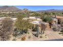 An aerial view of a tan home and desert landscaping in an upscale community with mountain views at 7322 E High Point Dr, Scottsdale, AZ 85266