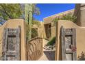 Rustic gated entrance to a tan home with cacti and desert landscaping creating a private oasis at 7322 E High Point Dr, Scottsdale, AZ 85266