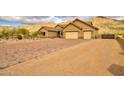 Stucco home features desert landscaping, brick driveway, tile roof and a three car garage on a sunny day at 8474 W Switchback Trl, Casa Grande, AZ 85194