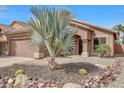 Attractive home featuring desert landscaping with rocks, cacti, and mature palm trees at 9706 E Sheena Dr, Scottsdale, AZ 85260