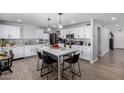 Bright kitchen features white cabinets, stainless steel appliances, a center island, and wood-look tile flooring at 10865 E Florian Ave, Mesa, AZ 85208
