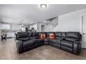 Spacious living room with an oversized leather couch, wood-look tile flooring, and an open floor plan at 10865 E Florian Ave, Mesa, AZ 85208