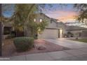 A cozy house exterior is shown with a driveway, landscape, and welcoming lighting at 4325 E Vallejo Ct, Gilbert, AZ 85298