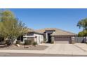 Well-manicured home exterior boasts a two-car garage, desert landscaping, and neutral color palette at 7024 W Tether Trl, Peoria, AZ 85383