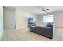 Comfortable living room featuring tile flooring, a gray sofa, and a ceiling fan at 24552 W Hilton Ave, Buckeye, AZ 85326