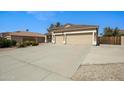 Spacious concrete driveway leading to a two-car garage, bordered by desert landscaping and a partial gate at 3336 E Thornton Ave, Gilbert, AZ 85297