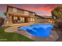 Inviting backyard with a sparkling pool, lush green lawn, and covered patio area at 45539 W Long Way, Maricopa, AZ 85139