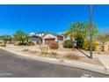 Suburban home with a red garage door, desert landscaping, and ample street parking under a cloudless blue sky at 14188 W Artemisa Ave, Surprise, AZ 85387
