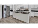 Modern kitchen featuring stainless steel appliances, dark countertops, white cabinets, and wood-look floors at 15093 W Glenrosa Ave, Goodyear, AZ 85395