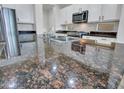 Kitchen island with dark countertop, stainless steel sink and faucet, and white cabinetry at 15093 W Glenrosa Ave, Goodyear, AZ 85395