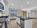 Open-concept kitchen featuring a kitchen island, stainless steel appliances, and wood-look floors at 15093 W Glenrosa Ave, Goodyear, AZ 85395