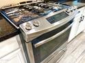Close-up of oven and stovetop with stainless steel finish, digital control panel, and dark countertops at 15093 W Glenrosa Ave, Goodyear, AZ 85395
