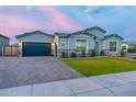 Charming single-story home featuring a well-manicured lawn, stone veneer, and a two-car garage with brick driveway at 17962 W Elm St, Goodyear, AZ 85395