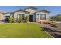 Well-maintained home featuring a lush green lawn and stone accents at the front exterior at 17962 W Elm St, Goodyear, AZ 85395
