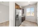 Kitchen displaying a stainless steel refrigerator, granite countertops, dark wood cabinetry, and natural light at 21292 N 270Th Dr, Buckeye, AZ 85396