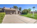 Well-maintained single-story home showcasing a concrete driveway, lush lawn, and mature landscaping at 25273 S Berry Brook Dr, Sun Lakes, AZ 85248