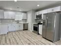 Modern kitchen featuring stainless steel appliances, white cabinets, and stylish wood-look flooring at 2634 N 52Nd Ave, Phoenix, AZ 85035