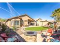 This backyard features an outdoor fire pit, covered patio, synthetic grass, desert plants, and lounge furniture at 31013 N Claridge Cir, San Tan Valley, AZ 85143
