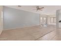 Bright living room with carpet, adjacent tile flooring, ceiling fan, and ample natural light at 41444 W Capistrano Dr, Maricopa, AZ 85138
