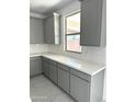 Well-lit kitchen with gray cabinets, white countertops and tiled backsplash at 43372 N Wollemi St, Queen Creek, AZ 85140