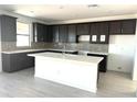 A modern kitchen with white countertops, an island, dark cabinetry, and stainless steel fixtures at 43373 N Wollemi St, Queen Creek, AZ 85140