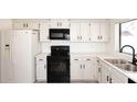 A kitchen with white cabinets, black hardware, stainless steel appliances, and light colored wood look floors at 4902 E Charter Oak Rd, Scottsdale, AZ 85254