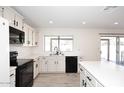 Kitchen featuring white cabinets, black appliances, tile floors, and a window with a view to the exterior at 4902 E Charter Oak Rd, Scottsdale, AZ 85254