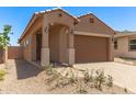 Inviting home featuring an arched entryway, desert landscaping, and a spacious two-car garage at 5641 N 205Th Ln, Buckeye, AZ 85396