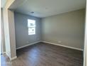This is a bedroom with wood-look tile floors, neutral walls and trim, and a window overlooking the front yard at 7267 E Hackamore Ln, San Tan Valley, AZ 85143