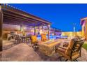 Inviting backyard featuring a pergola, fire pit, seating area, outdoor kitchen, and shimmering pool and spa at 10038 W Redbird Rd, Peoria, AZ 85383