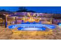 Lush backyard with a sparkling pool, spa, and multi-tiered landscaping complemented with vibrant uplighting at 10038 W Redbird Rd, Peoria, AZ 85383
