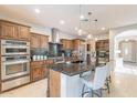 Gourmet kitchen with stainless steel appliances, rich cabinetry, and large center island with pendant lighting at 37148 N Stoneware Dr, Queen Creek, AZ 85140