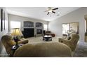 Bright living room with a fireplace, comfortable seating, and a ceiling fan for added comfort at 43271 W Mcclelland Dr, Maricopa, AZ 85138