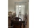 Dining room with a large wooden table and chairs, complemented by bright natural light and sheer curtains at 4604 E Summerhaven Dr, Phoenix, AZ 85044