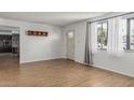 Bright living room with wood-look tile flooring, neutral walls, and natural light from a large window at 4728 N 61St Ave, Phoenix, AZ 85033
