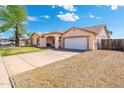 View of a tan single-story home with a two car garage and desert landscaping at 5115 W Kings Ave, Glendale, AZ 85306
