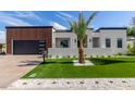 Beautiful modern home featuring a well-manicured lawn, stylish landscaping, and a sleek black garage door at 7325 E Virginia Ave, Scottsdale, AZ 85257