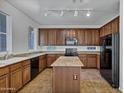 Open kitchen with brown cabinets, granite countertops, island, tile floors, and black appliances at 10132 E Isleta Ave, Mesa, AZ 85209