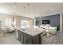 Open-concept living area with a large kitchen island, modern lighting, and stylish furnishings at 10251 W Gambit Trl, Peoria, AZ 85383