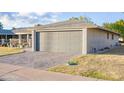 View of the two-car attached garage with brick-paved driveway, and low-maintenance landscaping at 10326 W Kingswood Cir, Sun City, AZ 85351