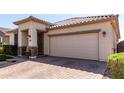 Attractive single-story home with neutral stucco, tile roof, brick accents, manicured lawn, and a two-car garage at 22607 W Antelope Trl, Buckeye, AZ 85326