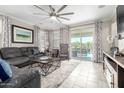 Bright living room with modern furniture, neutral tile floors, a large ceiling fan, and sliding glass doors at 22607 W Antelope Trl, Buckeye, AZ 85326