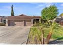 Inviting single-story residence featuring a well-maintained three-car garage, mature palm trees, and desert landscaping at 2894 E Melody Ln, Gilbert, AZ 85234