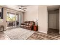 Comfortable living room with ceiling fan and sliding glass doors to a balcony, plus a brown leather couch at 3830 E Lakewood E Pkwy # 2042, Phoenix, AZ 85048